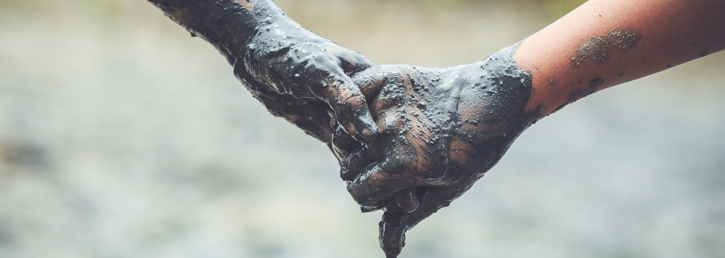 Two people holding hands while covered in mud.