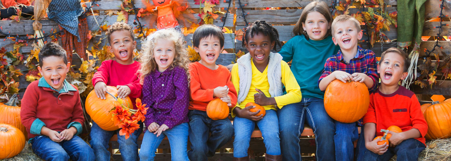 Children posing for a photo with pumpkins.