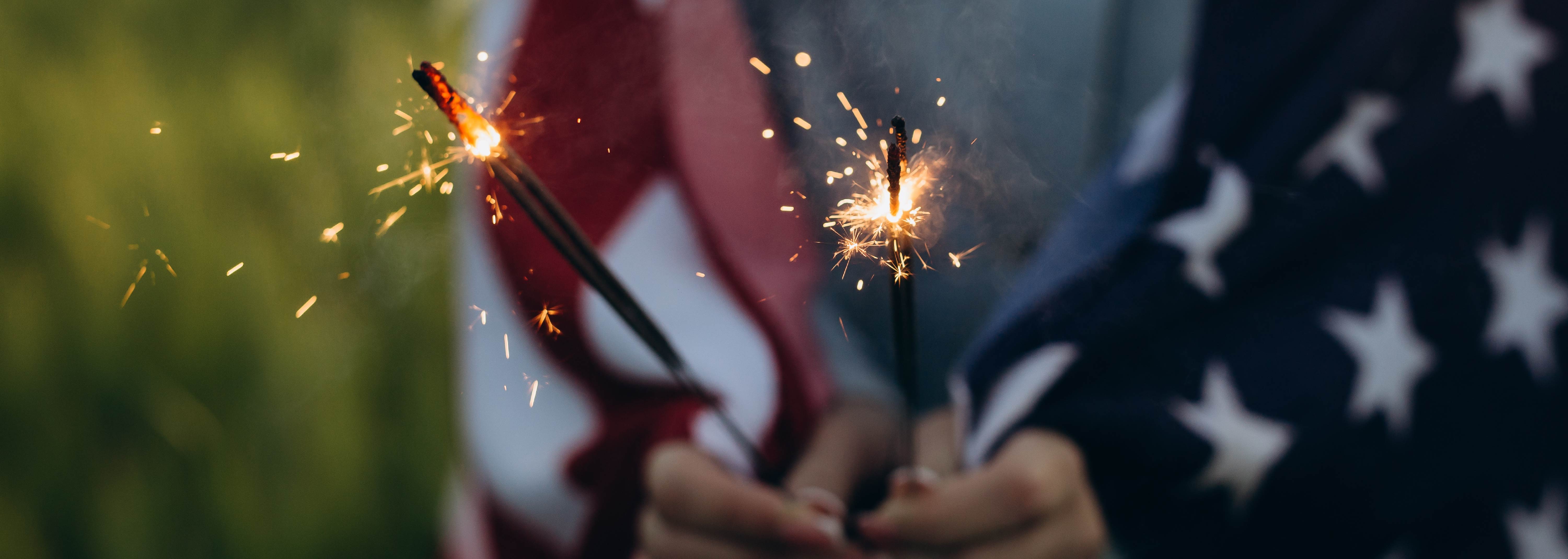 hands holding sparklers with flag