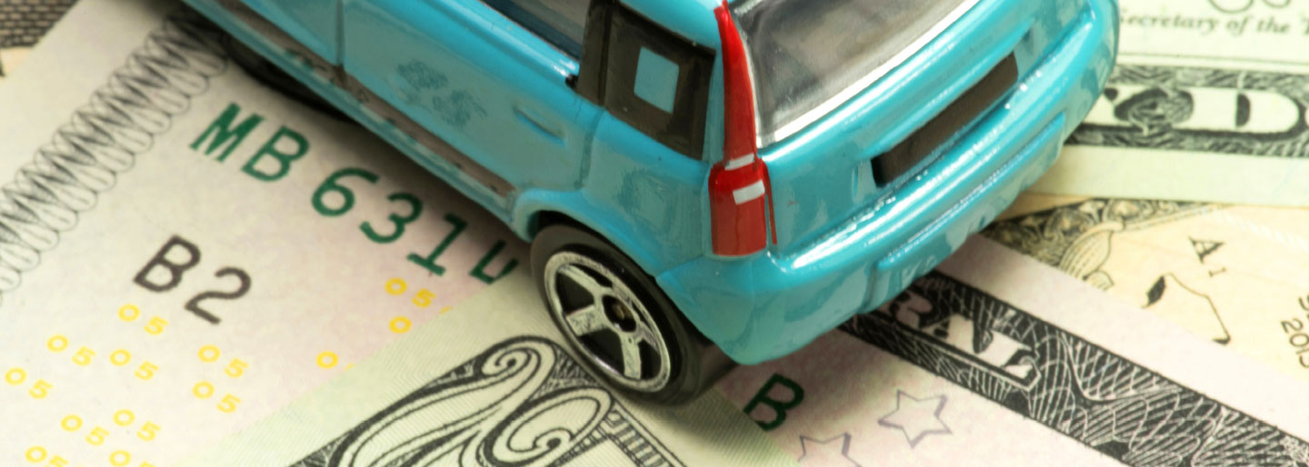 A toy car on a stack of bills.