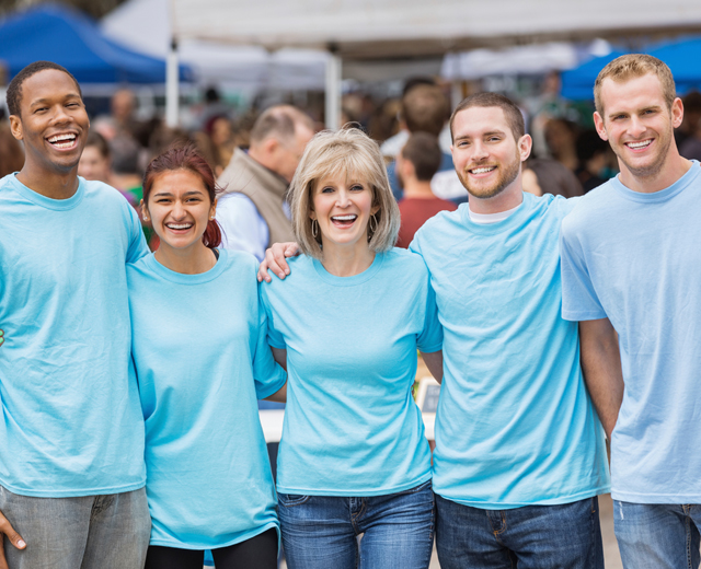 Women and men standing arm in arm in blue tshirts