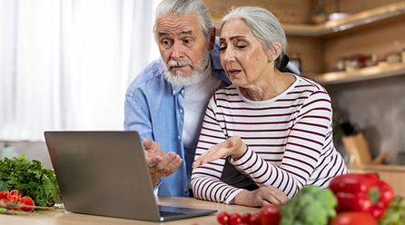 Older couple looking at laptop on the kitchen counter