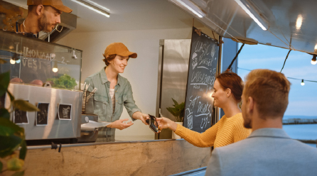Two people paying for food at counter using a debit card
