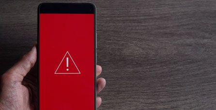 Phone screen with a red alert image on the front. 