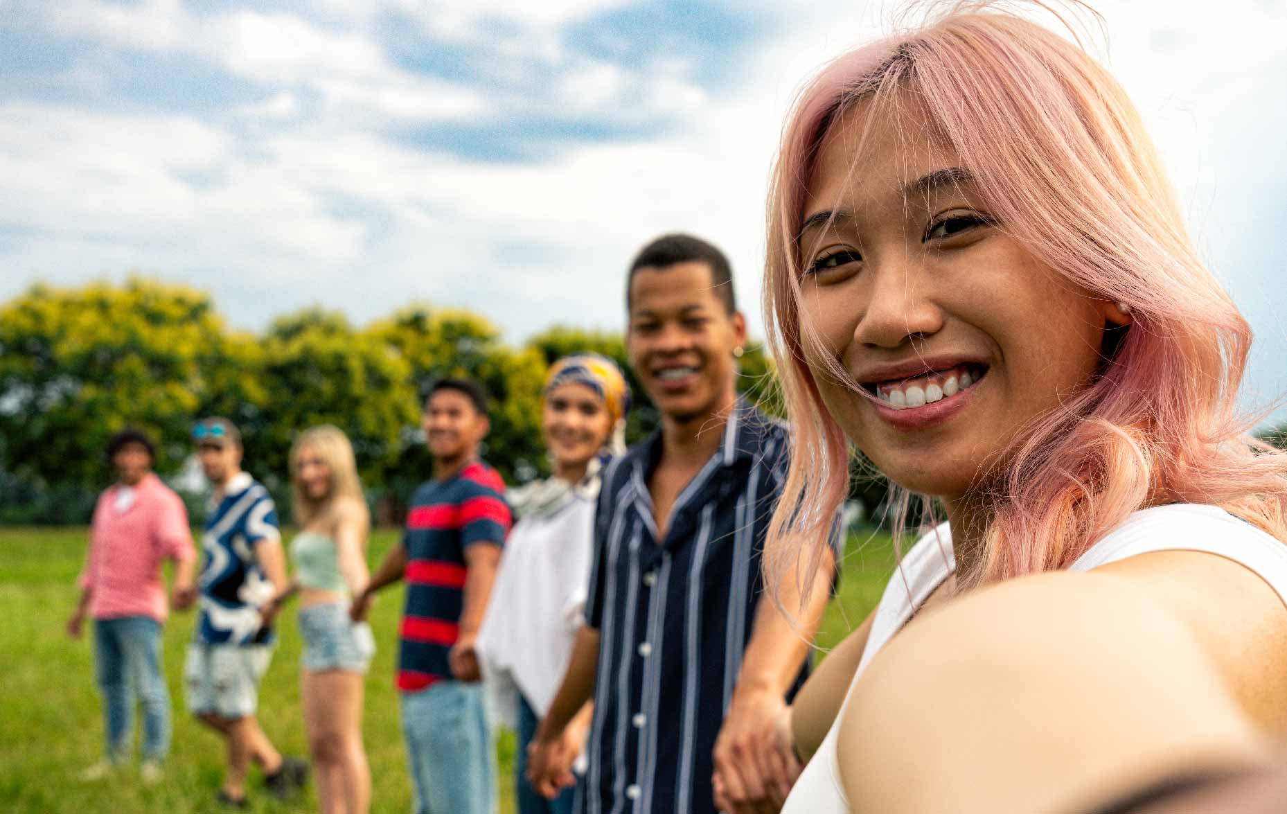 Group of young people smiling and holding hands while standing outside