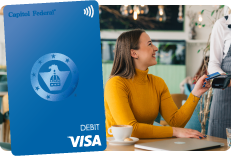 Woman using a debit card at a coffee shop with a True Blue debit card featured.
