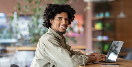 Man sitting at table in cafe and working on a laptop